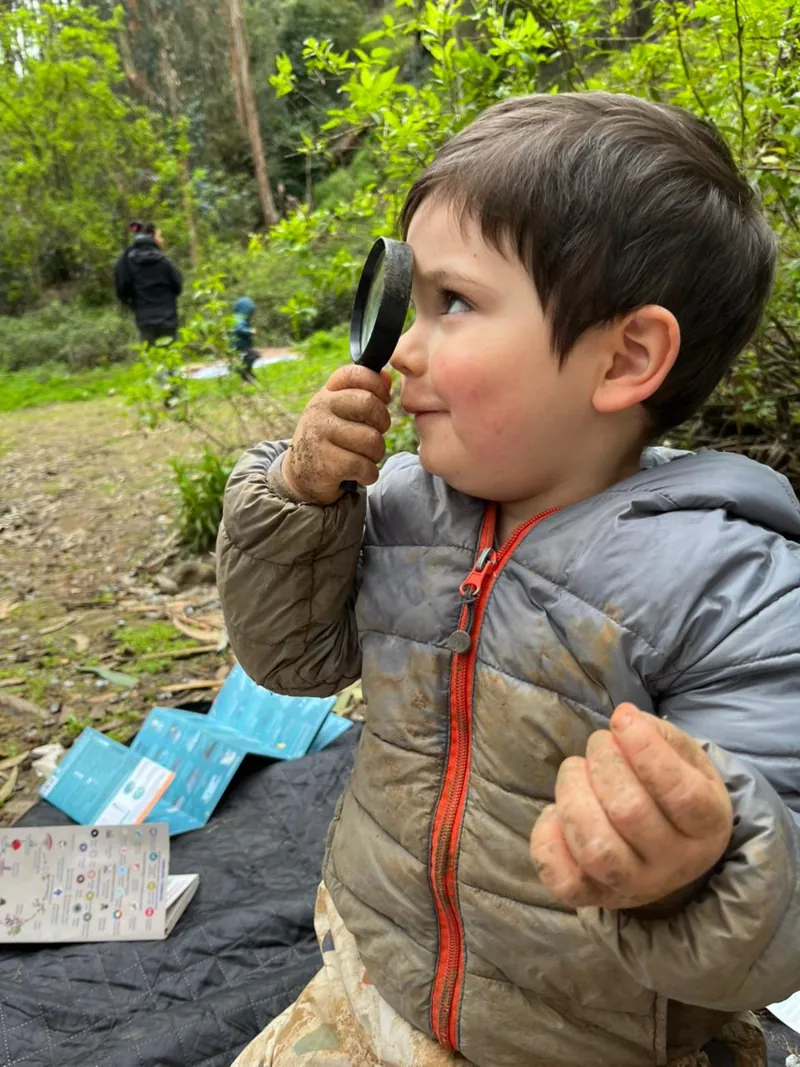 Un niño observa a través de una lupa durante una salida de exploración.