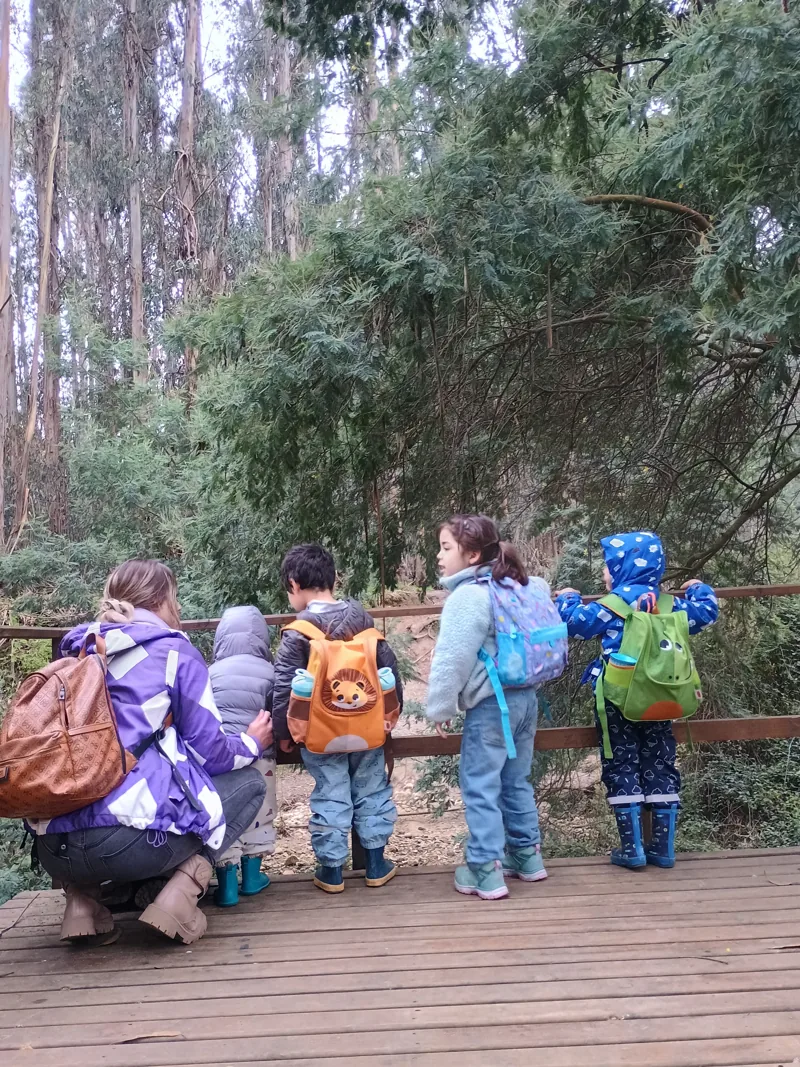 Una guía acompaña a un grupo de niños de Aurora en una salida a explorar la naturaleza.