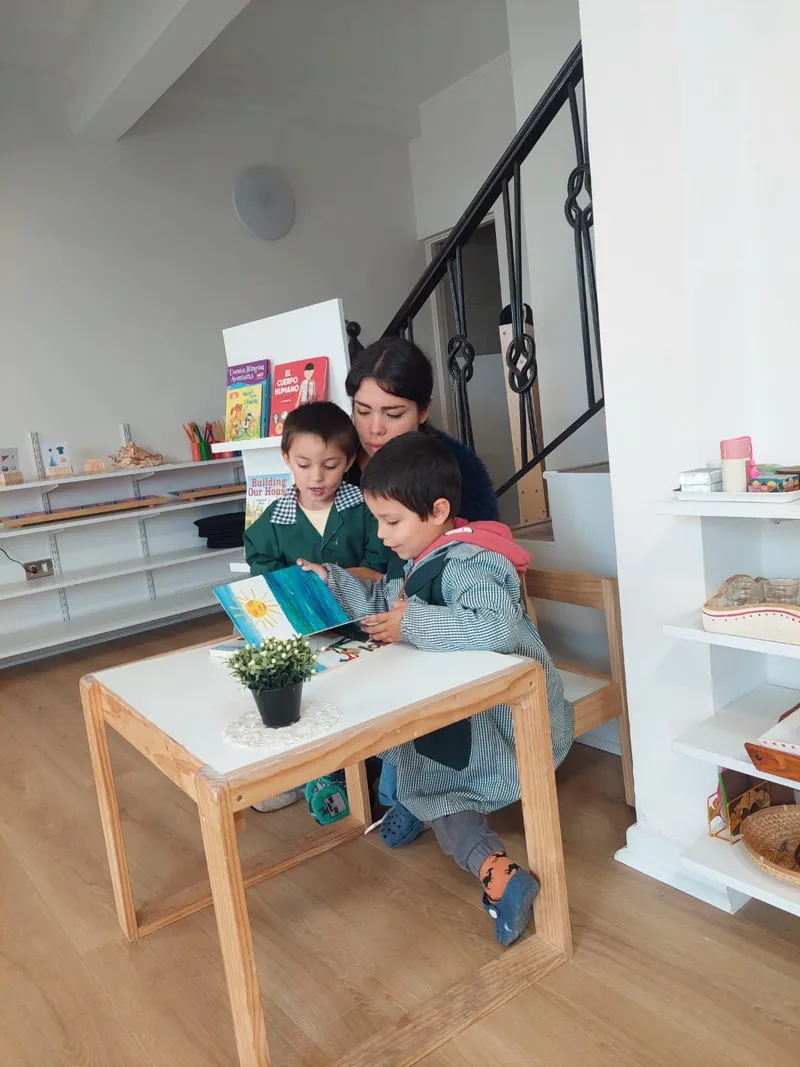 Dos niños miran un libro junto a una adulta en Aurora.