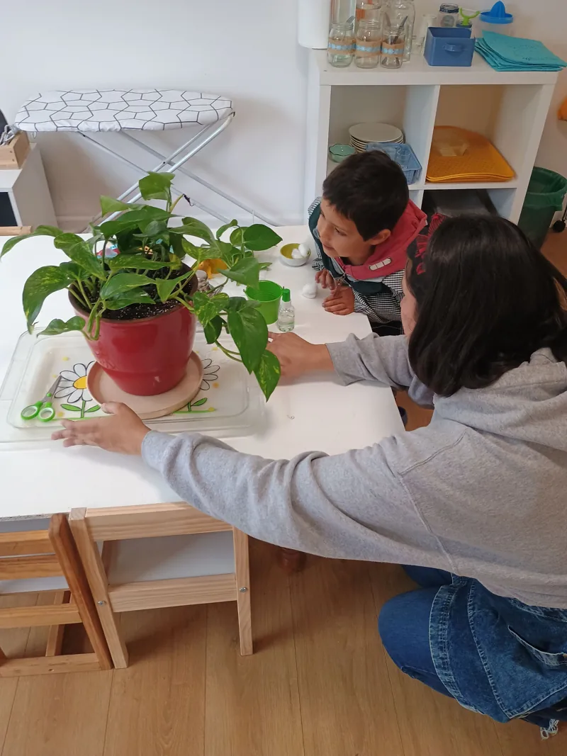 Un niño cuida una planta con el acompañamiento de una adulta en Aurora.