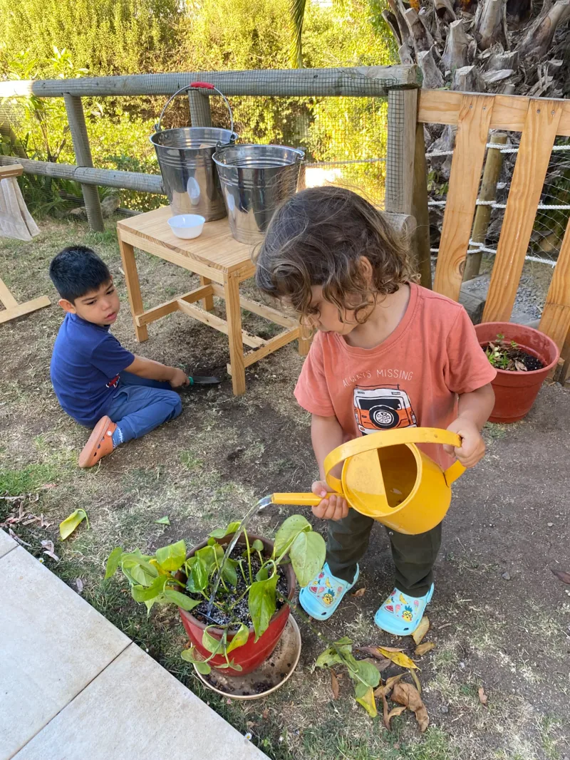 Una niña riega las plantas del jardín de Aurora.