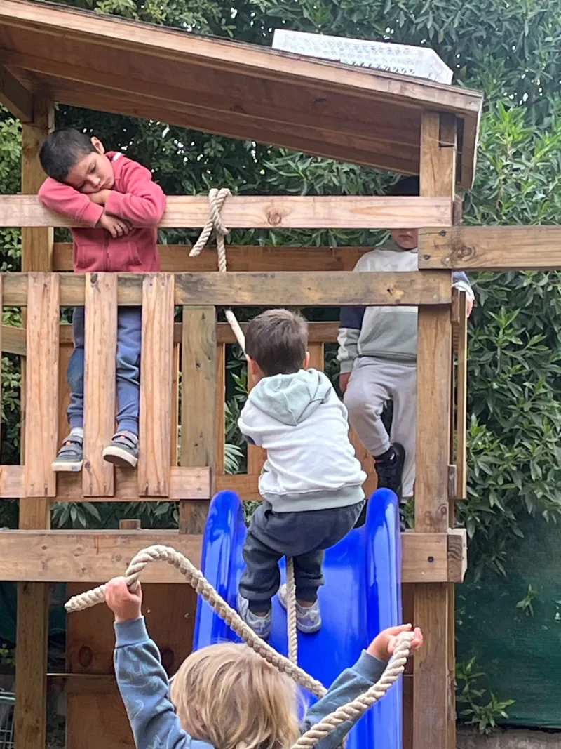 Niños exploran una estructura de madera en el patio de Aurora.
