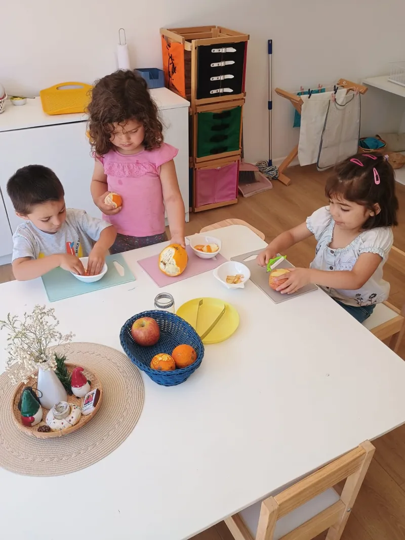 Tres niños preparan fruta en una mesa del ambiente de Aurora.