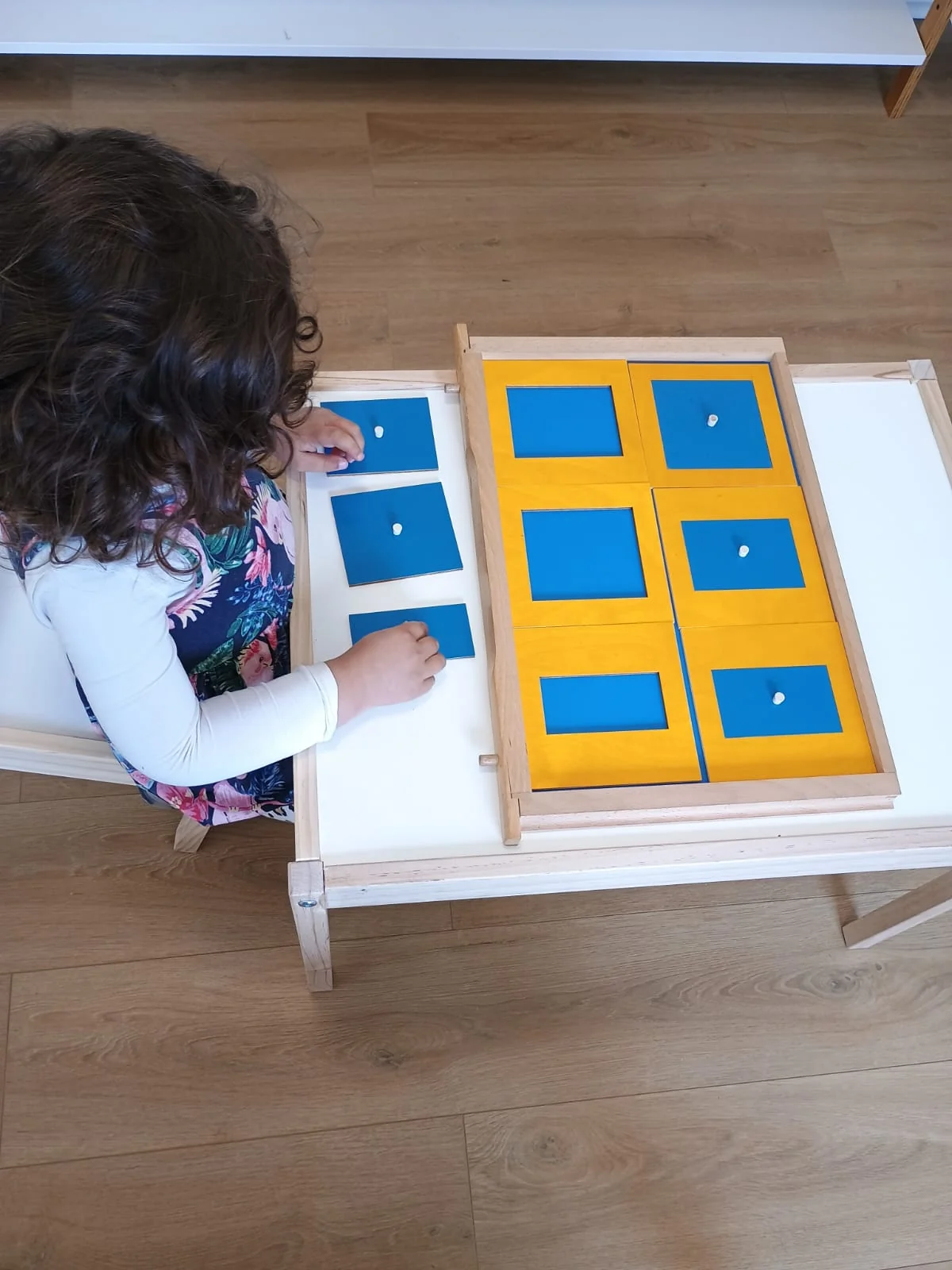 Una niña explora encajes geométricos Montessori en el ambiente de Aurora.